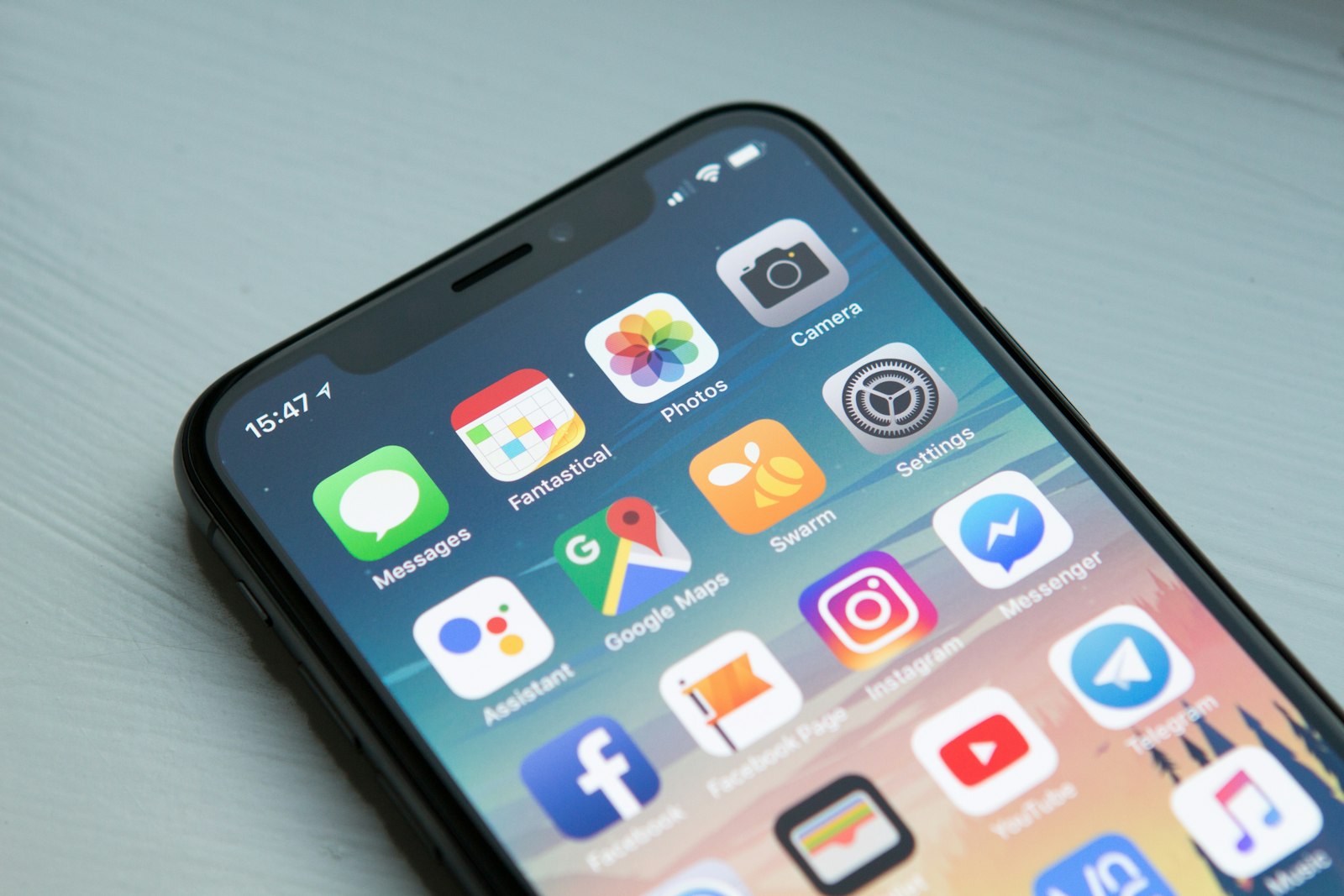 Primer plano de un iPhone sobre una mesa, con la pantalla de inicio y los iconos de las apps.