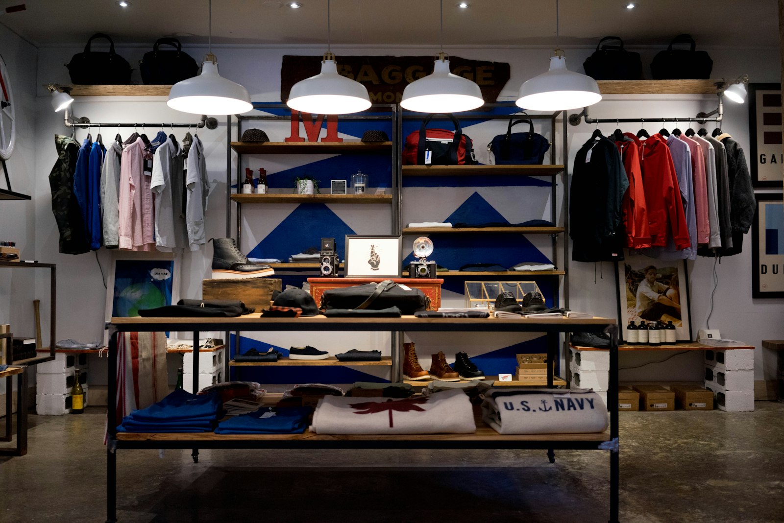 Interior de una tienda de ropa, con percheros, estantes y una mesa de camisetas en el centro.